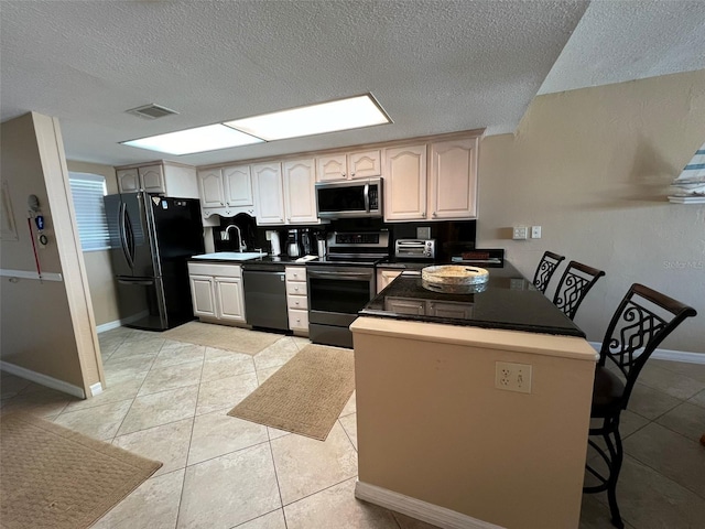 kitchen with light tile patterned floors, kitchen peninsula, sink, and black appliances