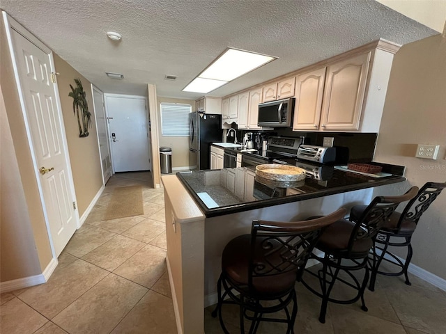 kitchen with electric stove, sink, a kitchen breakfast bar, black fridge, and kitchen peninsula