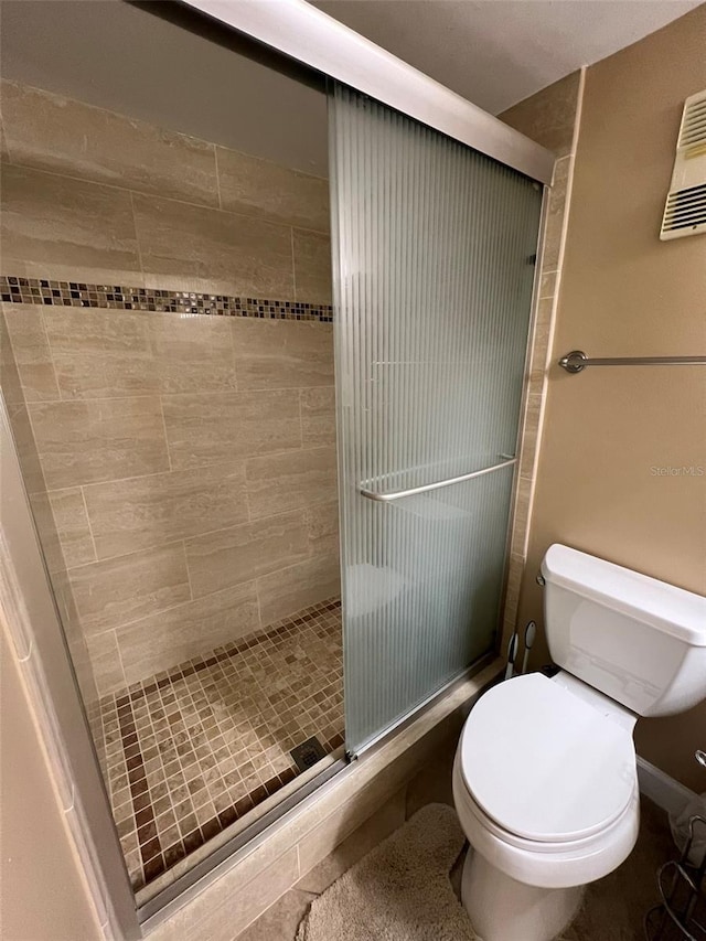 bathroom with toilet and a shower with shower door