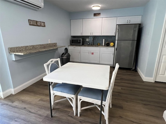 kitchen featuring appliances with stainless steel finishes, a wall mounted air conditioner, white cabinetry, backsplash, and kitchen peninsula