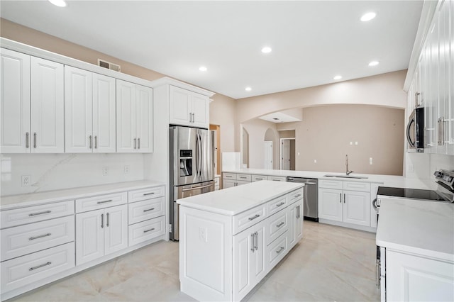 kitchen with sink, a center island, kitchen peninsula, stainless steel appliances, and white cabinets