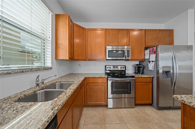 kitchen with light tile patterned flooring, sink, stainless steel appliances, light stone countertops, and a textured ceiling