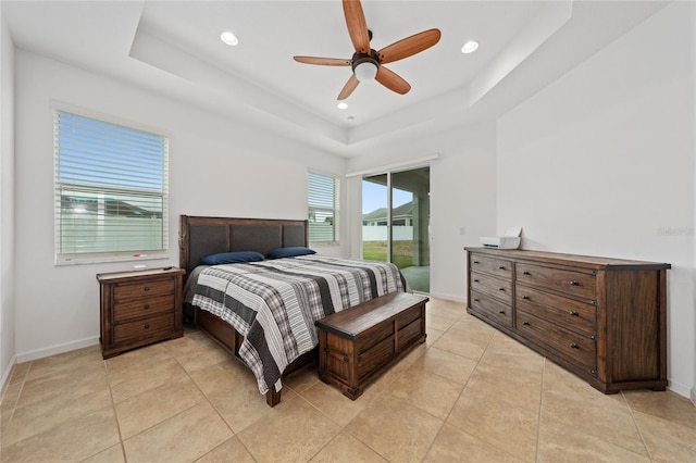 tiled bedroom featuring ceiling fan, a tray ceiling, and access to exterior