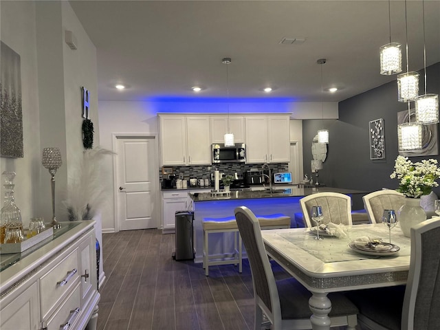 kitchen featuring pendant lighting, a breakfast bar, white cabinetry, backsplash, and dark hardwood / wood-style floors