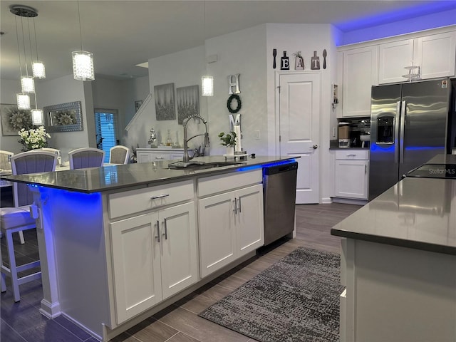 kitchen featuring sink, a breakfast bar area, an island with sink, stainless steel appliances, and white cabinets