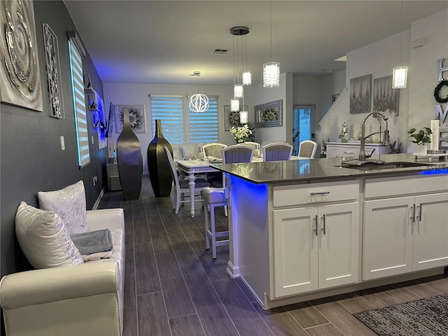 kitchen featuring pendant lighting, sink, a breakfast bar, white cabinets, and a kitchen island