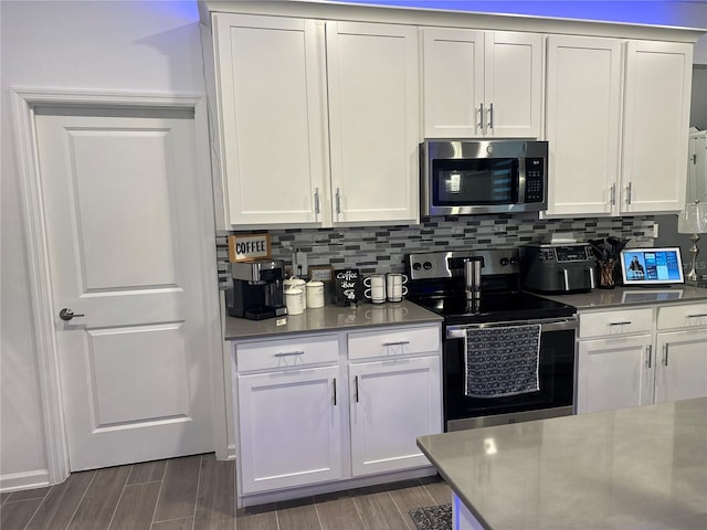 kitchen featuring decorative backsplash, stainless steel appliances, and white cabinets