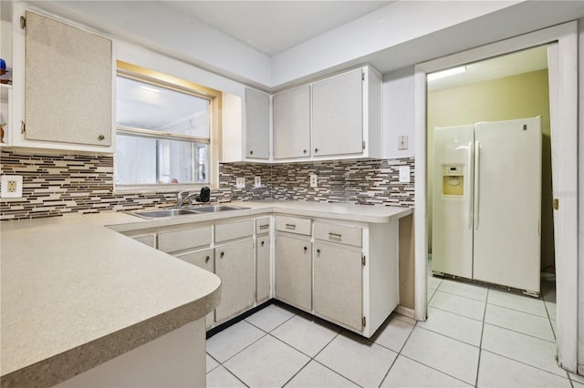 kitchen with backsplash, light tile patterned flooring, sink, and white fridge with ice dispenser