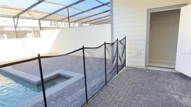 view of pool featuring a jacuzzi and glass enclosure