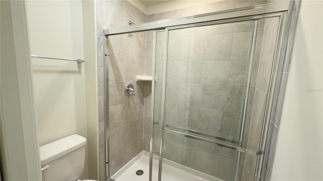 bathroom featuring toilet and a shower with door