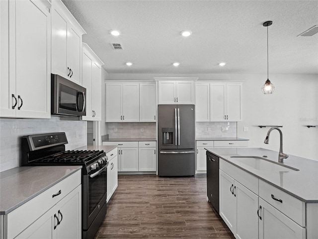 kitchen with white cabinetry, appliances with stainless steel finishes, sink, and pendant lighting