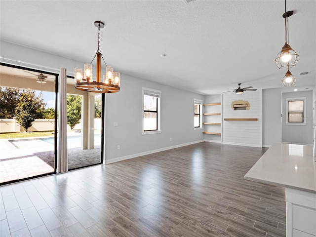 interior space with ceiling fan with notable chandelier, dark wood-type flooring, and a textured ceiling