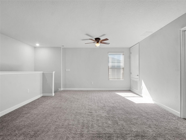 spare room with ceiling fan, light colored carpet, and a textured ceiling