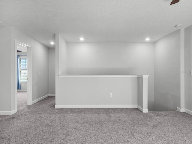 carpeted empty room with ceiling fan and a textured ceiling