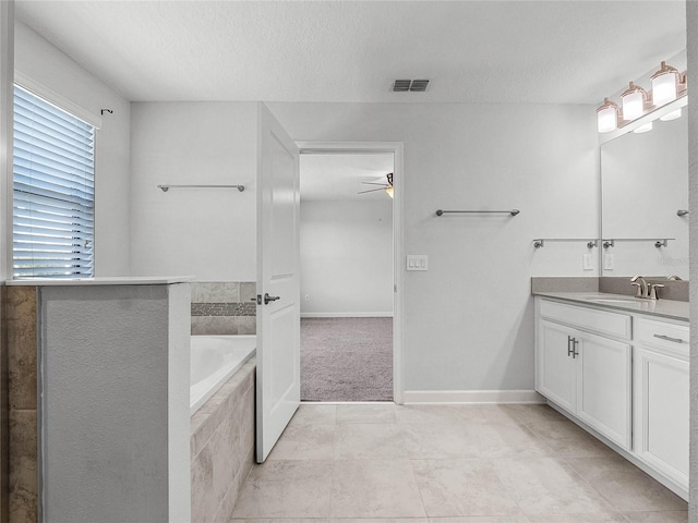 bathroom featuring vanity, tiled bath, and a textured ceiling