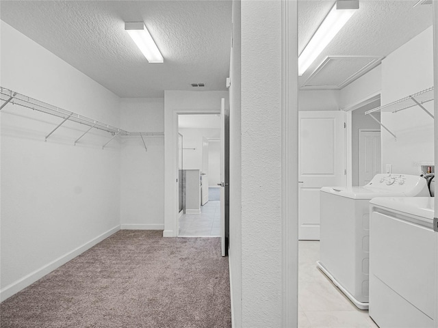 washroom with washing machine and clothes dryer, light carpet, and a textured ceiling