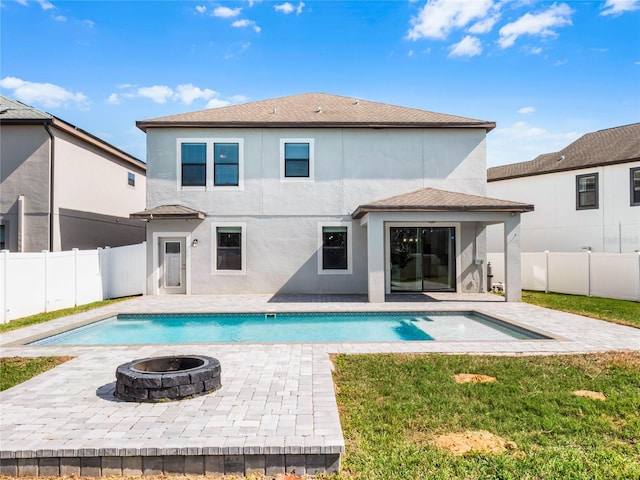 back of property with a fenced in pool, a patio area, and a fire pit