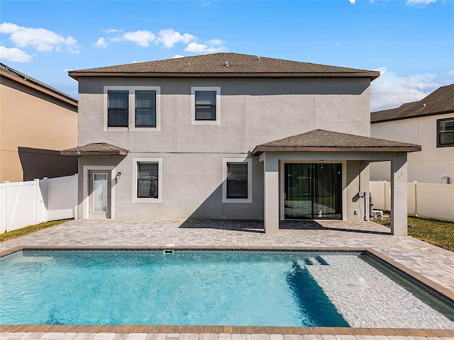 rear view of property with a fenced in pool and a patio area