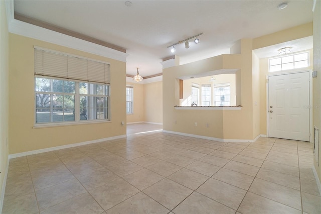 tiled spare room featuring ornamental molding and rail lighting