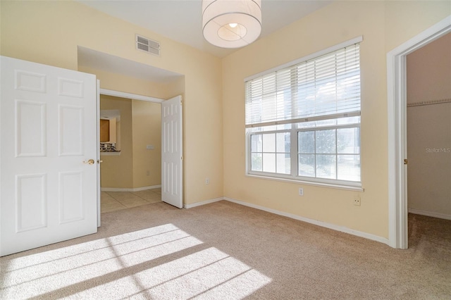 unfurnished bedroom featuring a spacious closet and light carpet