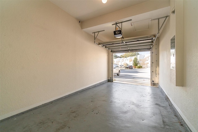 garage with a garage door opener, a textured wall, and baseboards