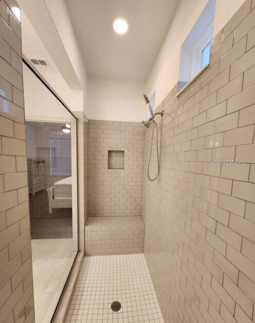 bathroom featuring tile patterned flooring, tile walls, and tiled shower