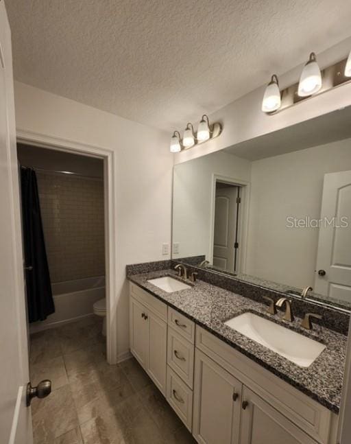 full bathroom with vanity, shower / bath combo, a textured ceiling, and toilet