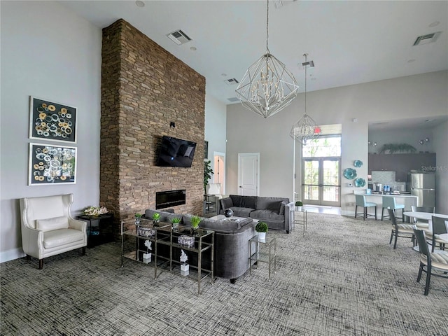 living room with carpet floors, a fireplace, a chandelier, and a high ceiling