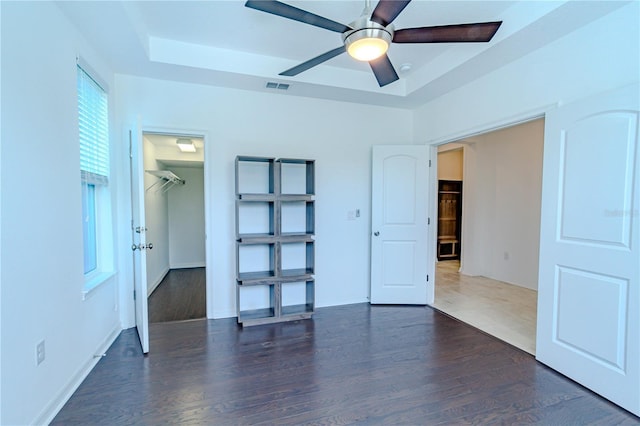 interior space with baseboards, visible vents, a raised ceiling, and wood finished floors