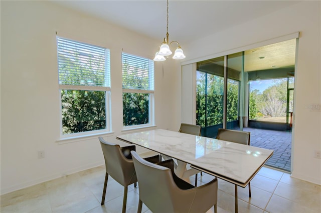 dining room with a chandelier, light tile patterned flooring, and baseboards