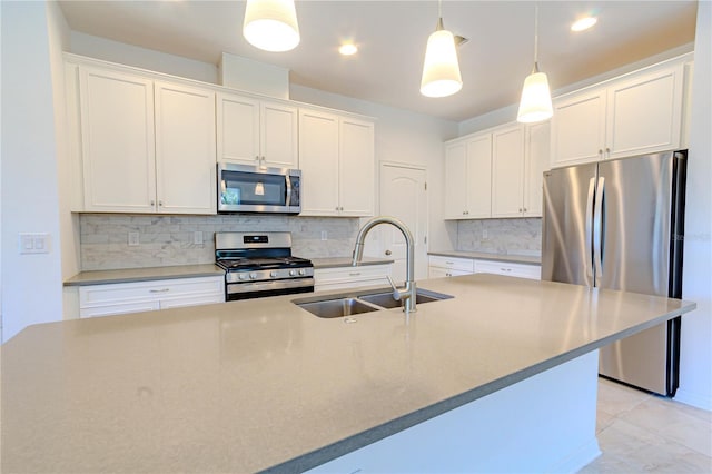 kitchen featuring tasteful backsplash, appliances with stainless steel finishes, white cabinetry, pendant lighting, and a sink