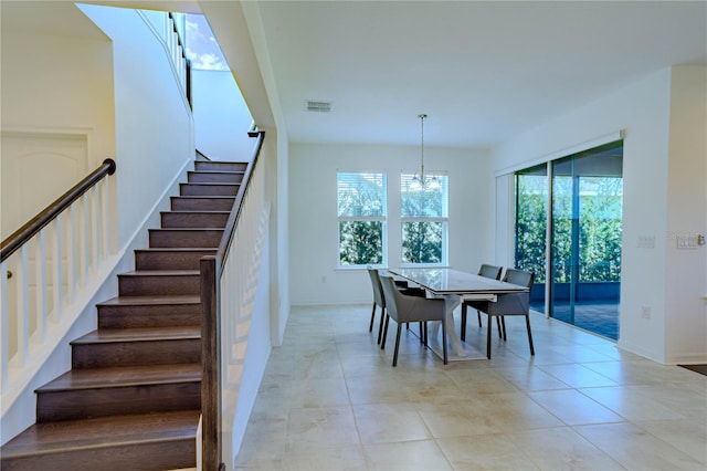 dining room featuring light tile patterned floors, visible vents, a notable chandelier, and stairs