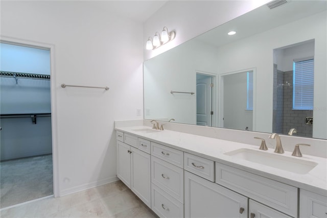 bathroom with double vanity, a shower stall, visible vents, and a sink