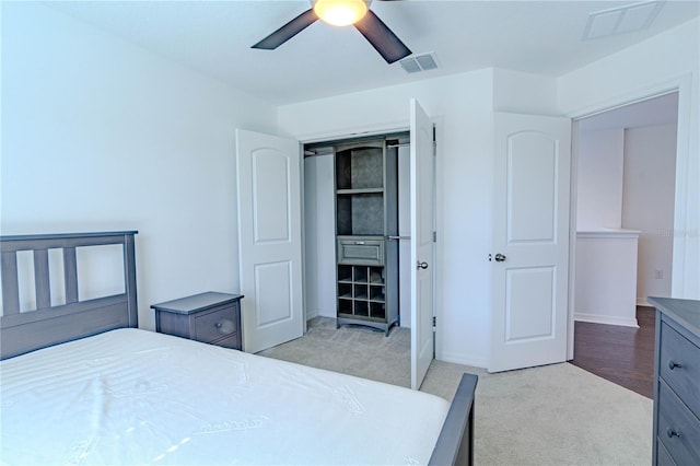 carpeted bedroom featuring a ceiling fan, visible vents, and baseboards