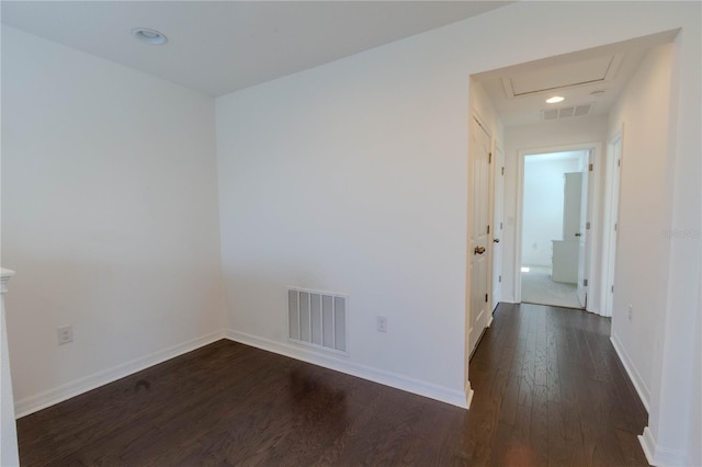 unfurnished room featuring dark wood-style flooring, visible vents, and baseboards