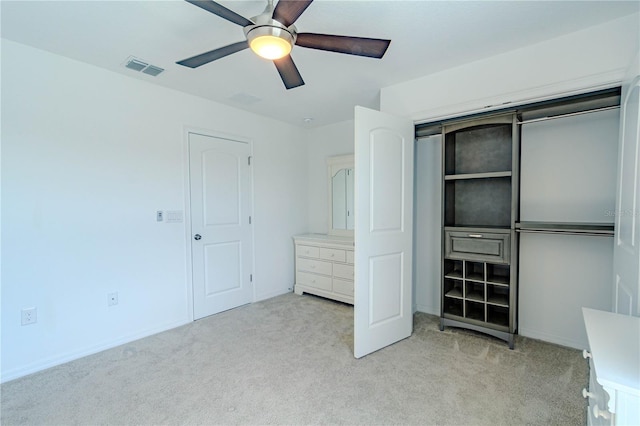 unfurnished bedroom featuring a ceiling fan, a closet, light colored carpet, and visible vents