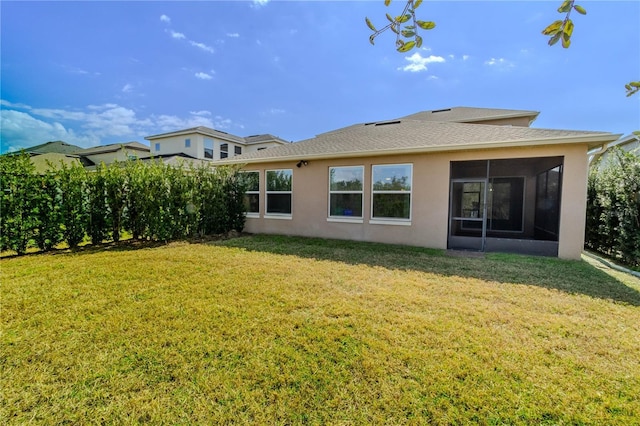 back of property with a shingled roof, a lawn, a sunroom, and stucco siding