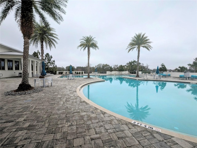 community pool with a patio area and fence