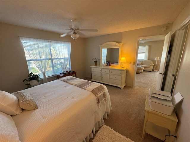 carpeted bedroom with ceiling fan, multiple windows, and a textured ceiling