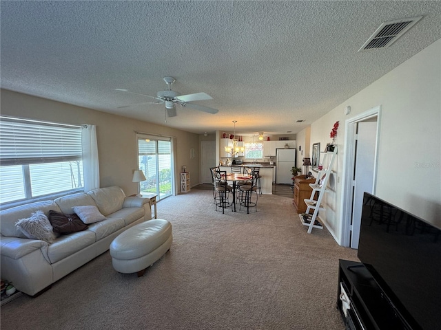 living room featuring light carpet, a textured ceiling, and ceiling fan