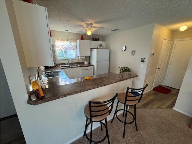 kitchen with sink, white appliances, white cabinetry, a textured ceiling, and kitchen peninsula