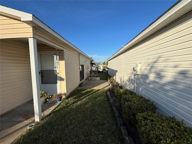 view of side of home with a patio and a lawn