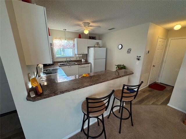 482 Hildalgo Dr, The Villages, FL 32159 - kitchen with white appliances, a sink, dark countertops, a peninsula, and a ceiling fan