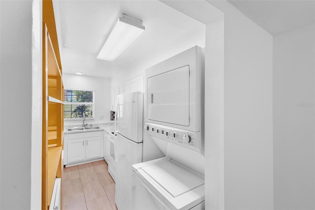 laundry area featuring stacked washer and clothes dryer, sink, and baseboard heating