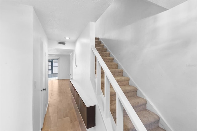 stairs featuring hardwood / wood-style flooring and a textured ceiling