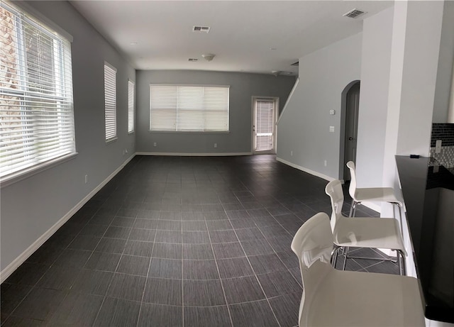 unfurnished living room with dark tile patterned floors and a healthy amount of sunlight