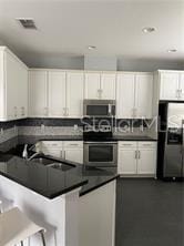 kitchen featuring a breakfast bar area, white cabinetry, appliances with stainless steel finishes, kitchen peninsula, and decorative backsplash