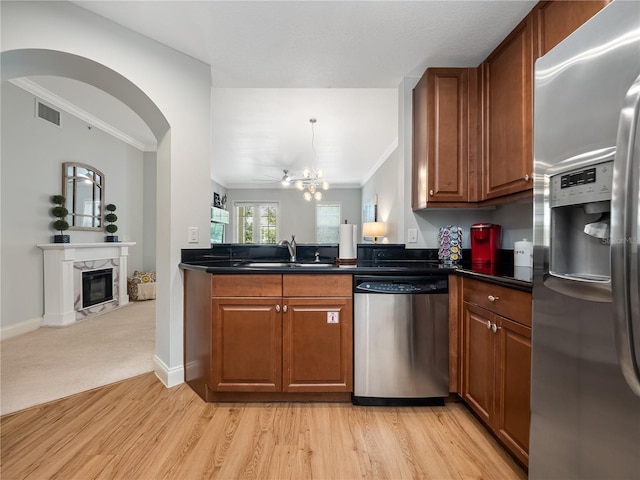 kitchen featuring appliances with stainless steel finishes, a fireplace, sink, crown molding, and light wood-type flooring