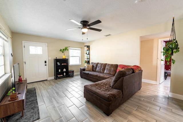 living room featuring ceiling fan and a textured ceiling