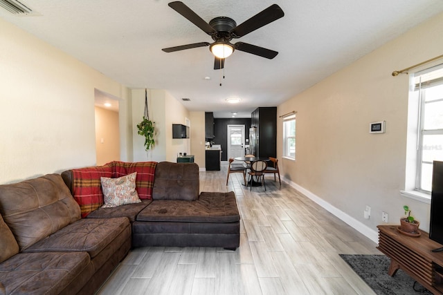 living room featuring plenty of natural light, ceiling fan, and light wood-type flooring